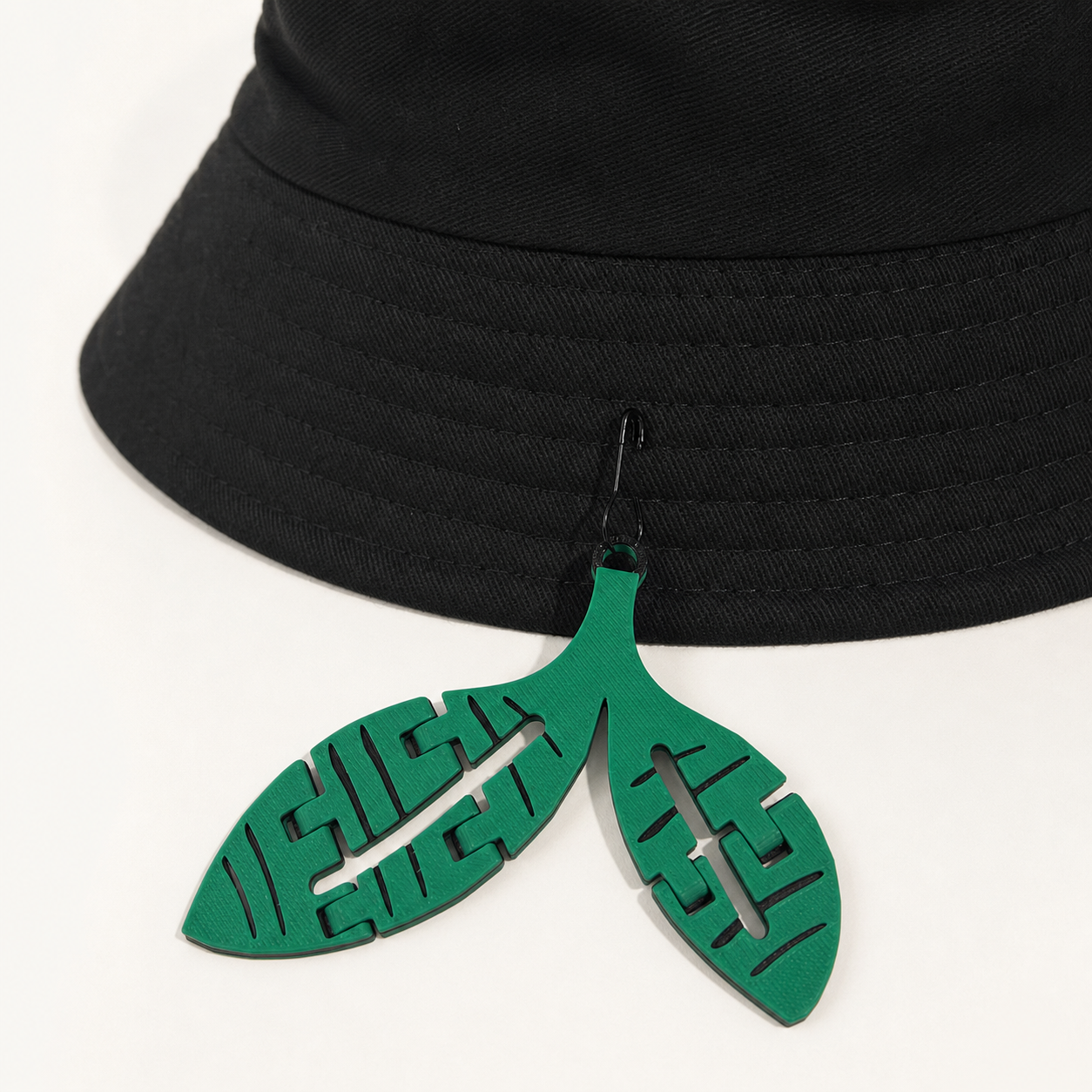 Green-and-black Sprout trinket attached to a black hat with its included black bulb pin